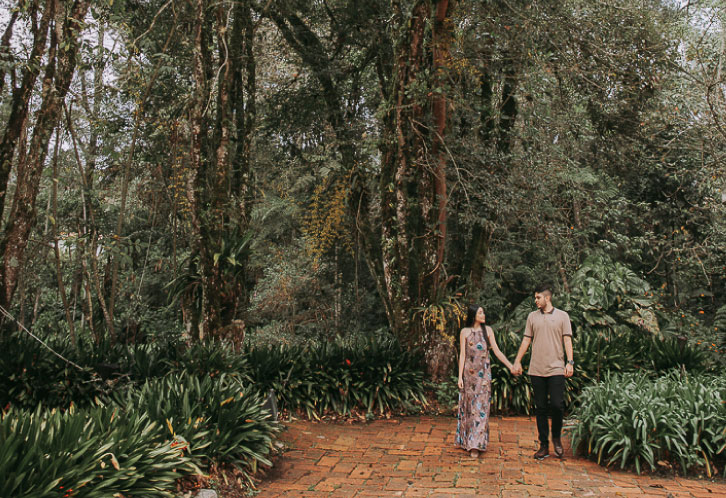 Pareja de novios caminando en el bosque cogidos de la mano